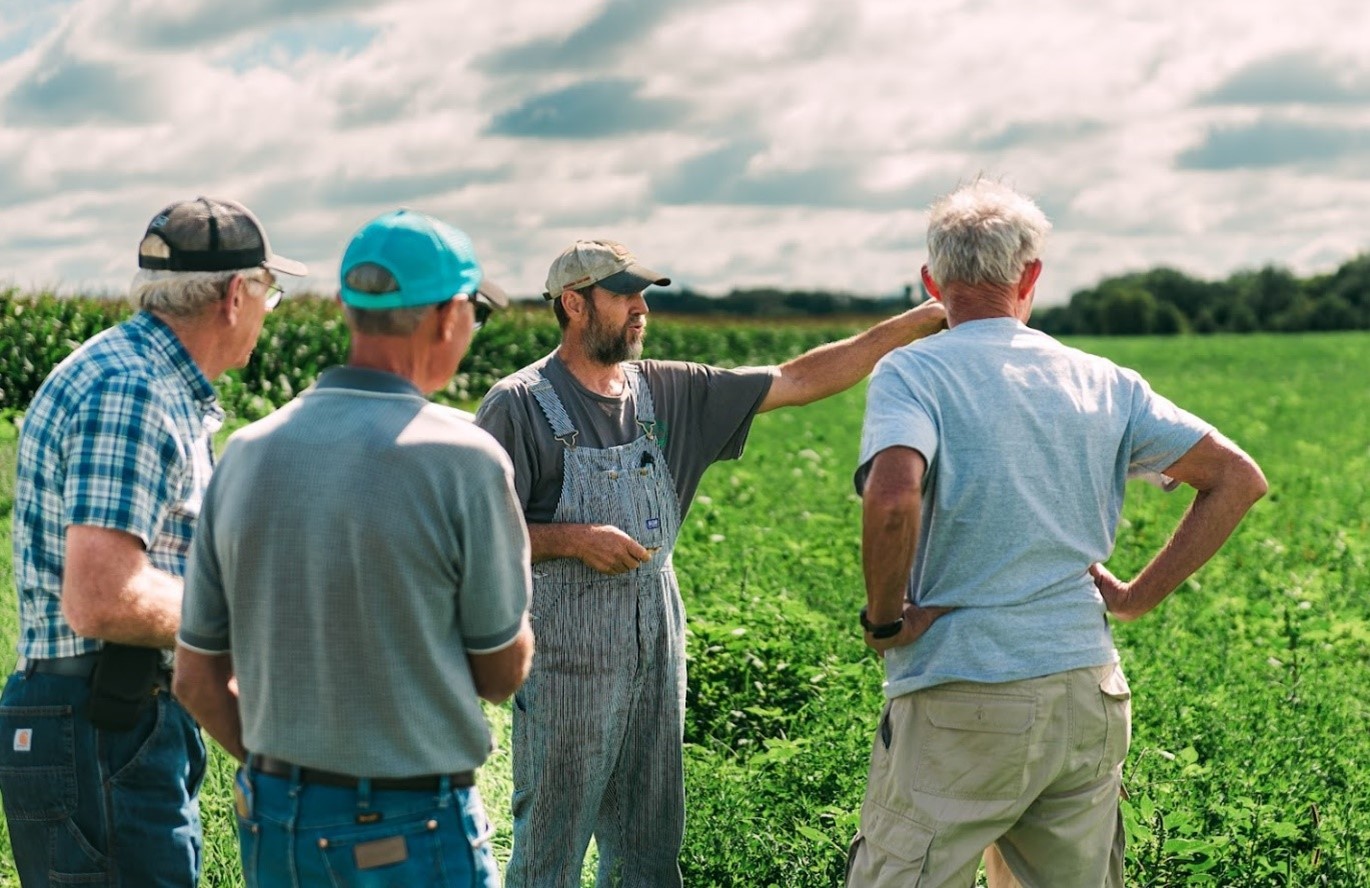 four men standing in a field talking